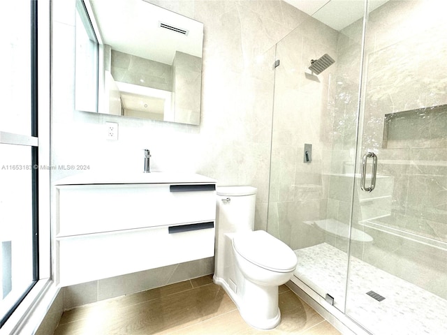 bathroom with vanity, toilet, and a shower with door