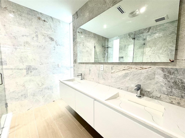 bathroom featuring walk in shower, vanity, and tile walls