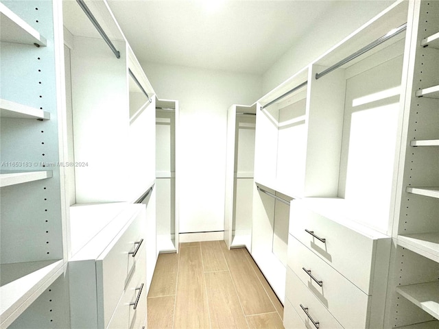 walk in closet with light hardwood / wood-style floors