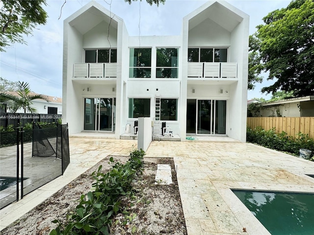 rear view of house with a fenced in pool, a balcony, and a patio area