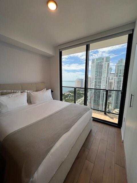 bedroom with floor to ceiling windows and hardwood / wood-style floors