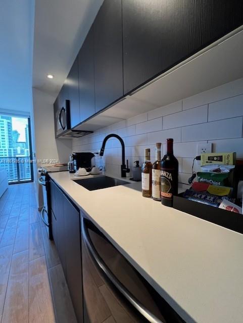 kitchen with light wood-type flooring, sink, backsplash, and stainless steel range with electric cooktop