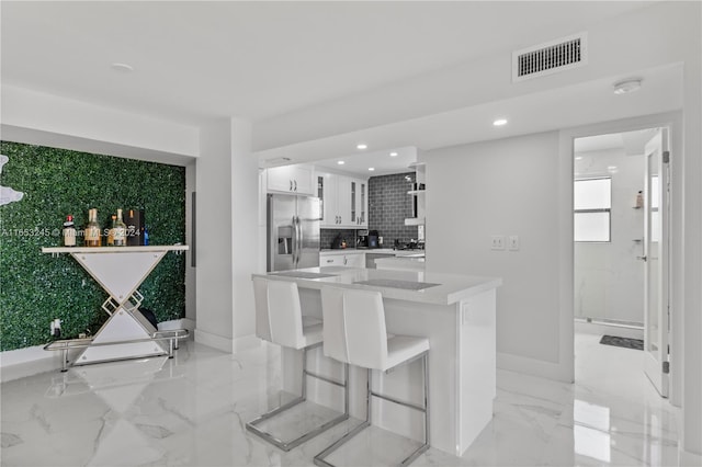 kitchen featuring white cabinetry, a breakfast bar area, backsplash, and stainless steel fridge with ice dispenser