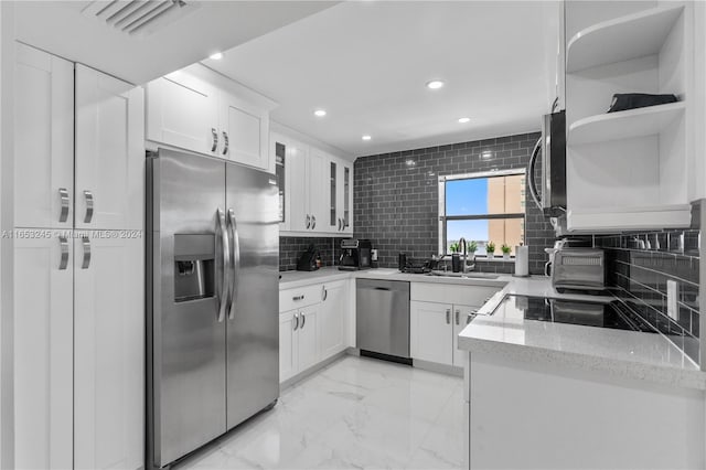 kitchen featuring white cabinetry, tasteful backsplash, stainless steel appliances, light stone counters, and sink