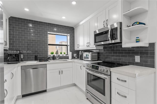 kitchen with white cabinets, light stone countertops, stainless steel appliances, sink, and tasteful backsplash