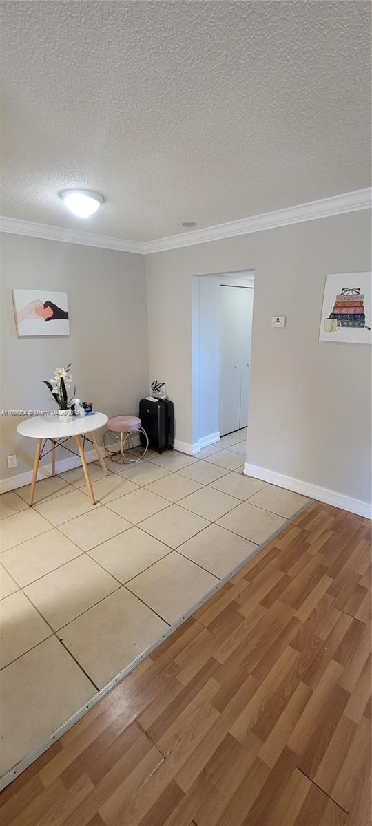 unfurnished room featuring a textured ceiling, ornamental molding, and light hardwood / wood-style floors