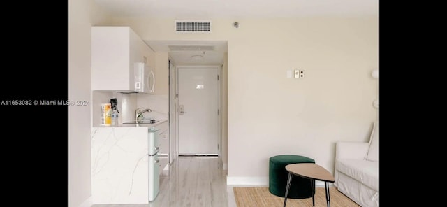 kitchen featuring light wood-type flooring and white cabinets