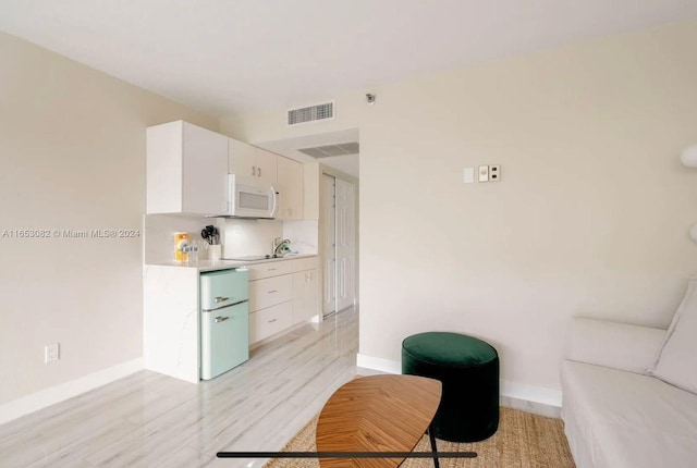 kitchen featuring decorative backsplash, white cabinetry, and light hardwood / wood-style floors