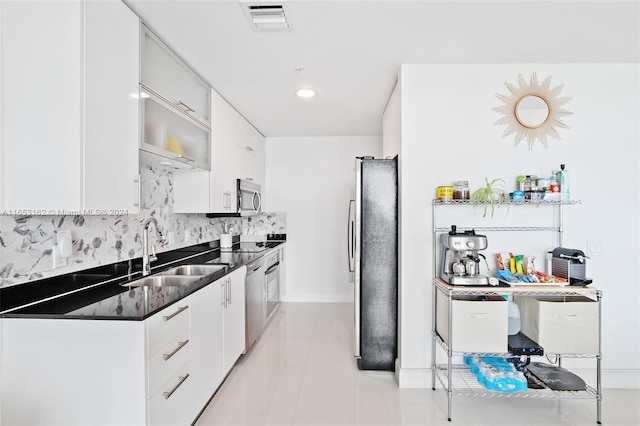 kitchen with backsplash, stainless steel appliances, white cabinets, and sink