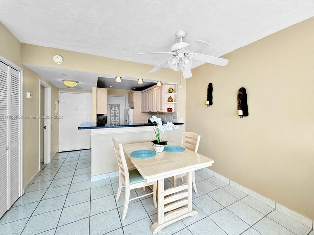 tiled dining space featuring a textured ceiling and ceiling fan