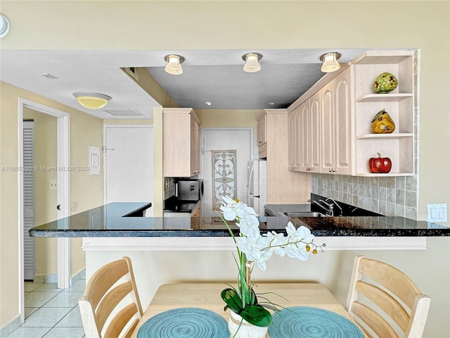 kitchen with backsplash, light tile patterned floors, white refrigerator, light brown cabinets, and kitchen peninsula