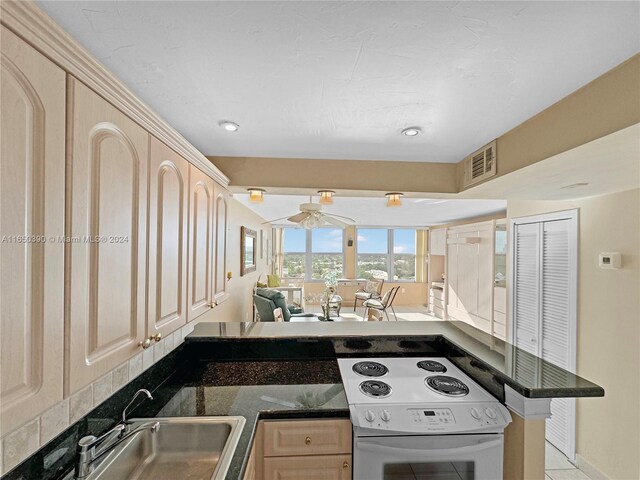 kitchen with light brown cabinetry, light tile patterned floors, kitchen peninsula, white electric stove, and dark stone counters