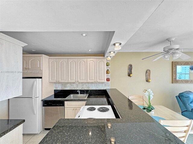 kitchen with white appliances, dark stone countertops, backsplash, sink, and ceiling fan