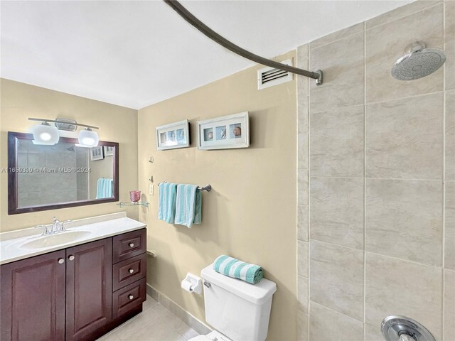 bathroom with tile patterned flooring, vanity, toilet, and a tile shower