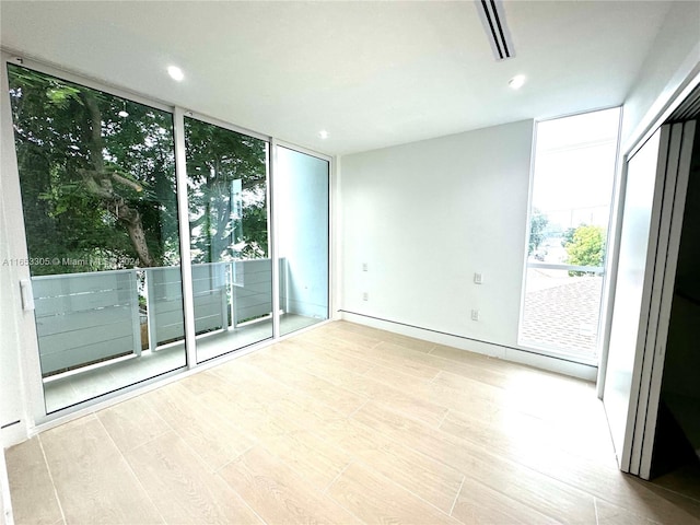 unfurnished room featuring floor to ceiling windows and light hardwood / wood-style floors