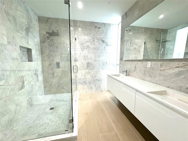 bathroom with wood-type flooring, tile walls, vanity, and a shower with shower door