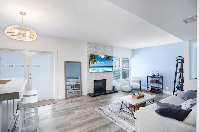 living room featuring baseboards, a fireplace, visible vents, and wood finished floors