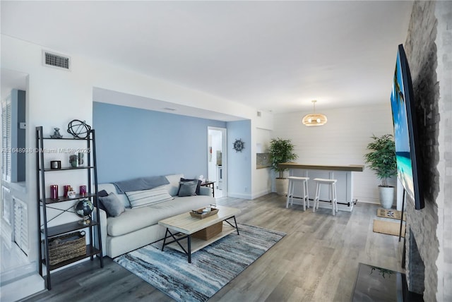 living area with wood finished floors, visible vents, and baseboards