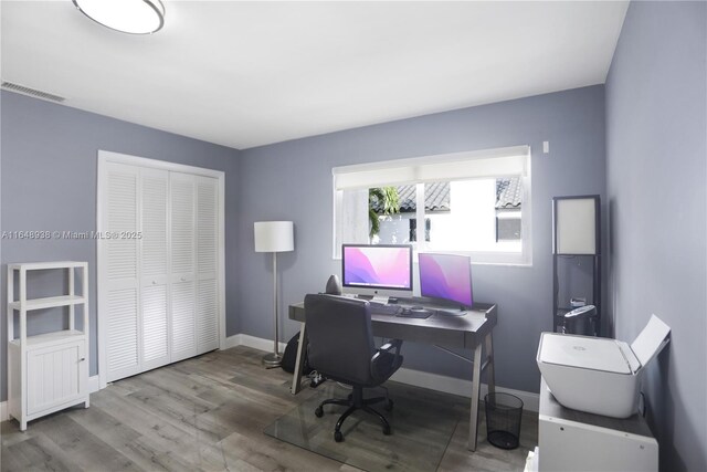 office area with visible vents, baseboards, and wood finished floors