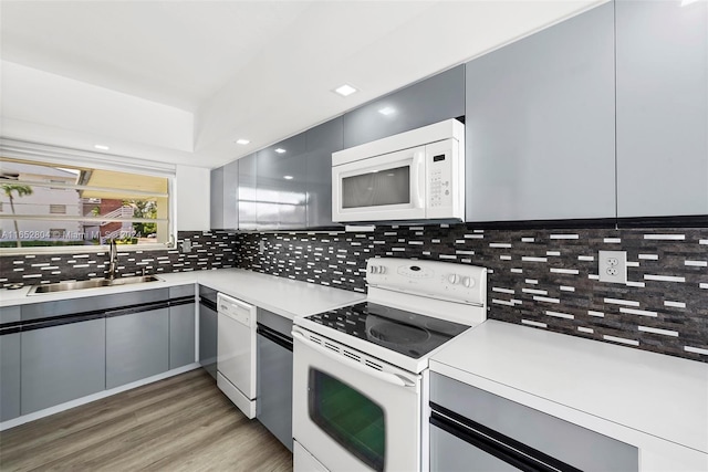 kitchen featuring light wood-type flooring, sink, white appliances, and decorative backsplash