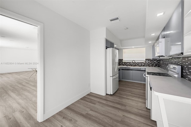 kitchen featuring light hardwood / wood-style floors, sink, white appliances, and decorative backsplash