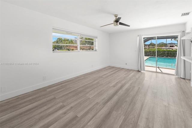 empty room with a healthy amount of sunlight, light hardwood / wood-style flooring, and ceiling fan