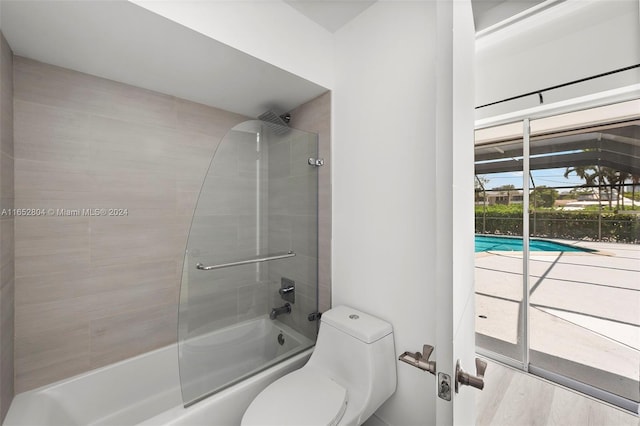 bathroom featuring tiled shower / bath, toilet, and hardwood / wood-style flooring