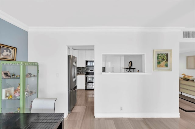 interior space featuring light hardwood / wood-style flooring, appliances with stainless steel finishes, white cabinetry, decorative backsplash, and ornamental molding