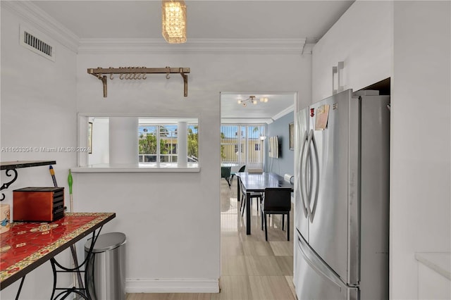 kitchen with ornamental molding and stainless steel refrigerator