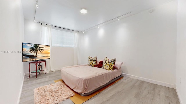 bedroom featuring track lighting and light hardwood / wood-style flooring