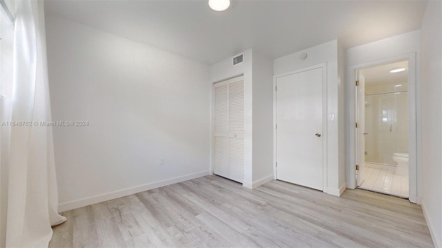 unfurnished bedroom with connected bathroom, a closet, and light hardwood / wood-style floors