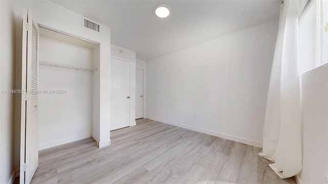 unfurnished bedroom featuring light hardwood / wood-style flooring and a closet