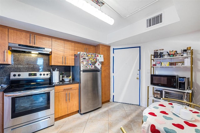 kitchen with appliances with stainless steel finishes, tasteful backsplash, and light tile patterned floors