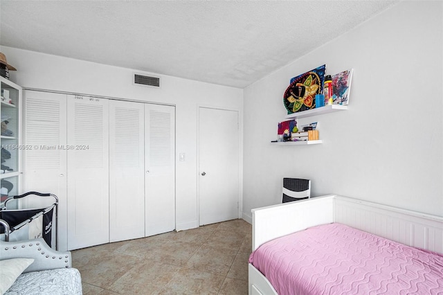 bedroom featuring a textured ceiling, light tile patterned floors, and a closet