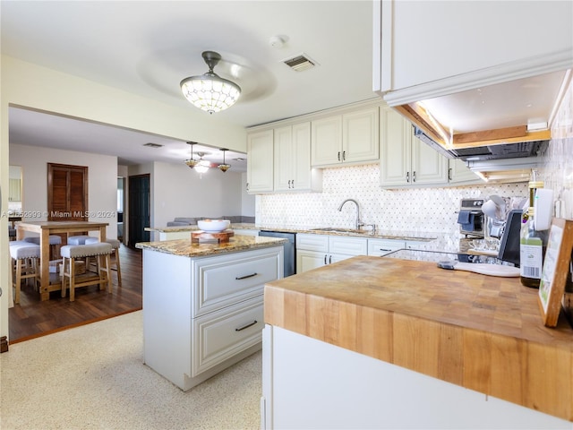 kitchen with hardwood / wood-style floors, a kitchen island, white cabinetry, and sink