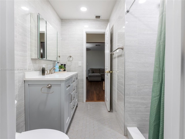 bathroom featuring vanity, toilet, a shower with curtain, and tile walls