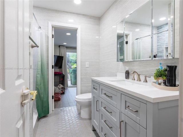 bathroom featuring tile patterned flooring, toilet, tile walls, a shower with curtain, and vanity