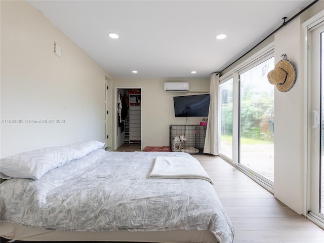 bedroom with a wall mounted AC, access to outside, and light hardwood / wood-style floors