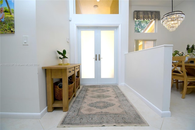 tiled foyer featuring a towering ceiling, an inviting chandelier, and french doors