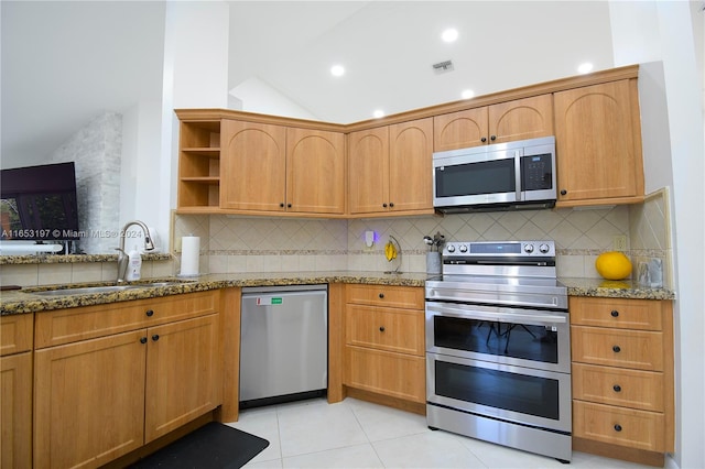 kitchen with stainless steel appliances, stone countertops, sink, tasteful backsplash, and light tile patterned floors