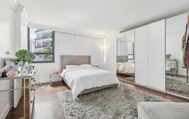 bedroom with ornamental molding and dark wood-type flooring