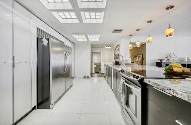 kitchen featuring light stone counters, sink, white electric range, stainless steel fridge, and pendant lighting