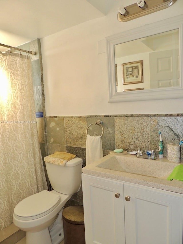 bathroom with vanity, toilet, tile walls, and tasteful backsplash