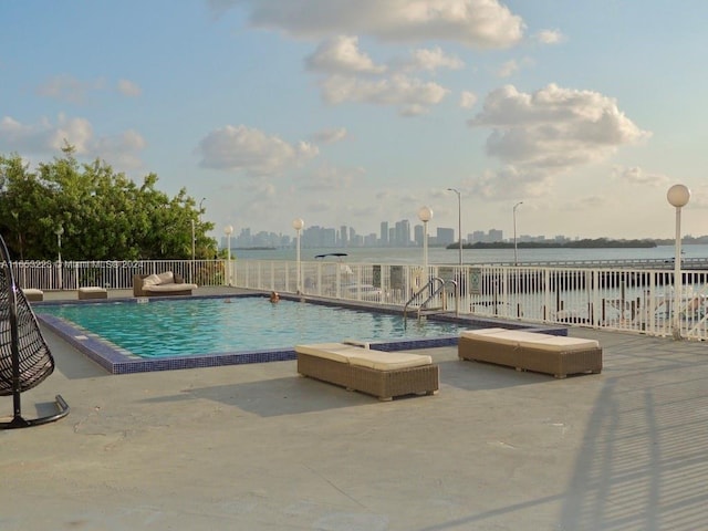 view of swimming pool featuring a water view and a patio area