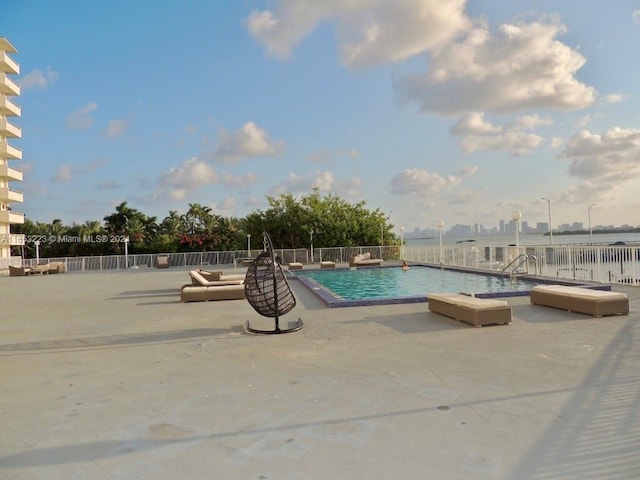 view of swimming pool featuring a water view and a patio area