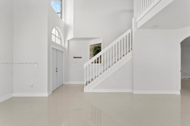 foyer entrance with a towering ceiling and light tile patterned floors