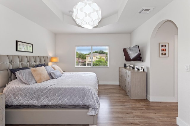 bedroom featuring light hardwood / wood-style flooring and a raised ceiling