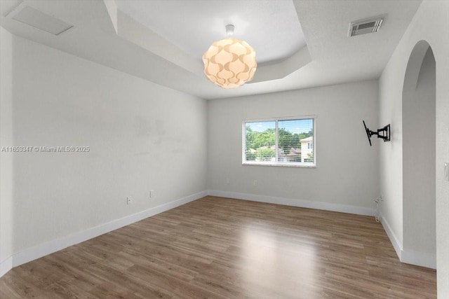 unfurnished room with hardwood / wood-style floors and a raised ceiling