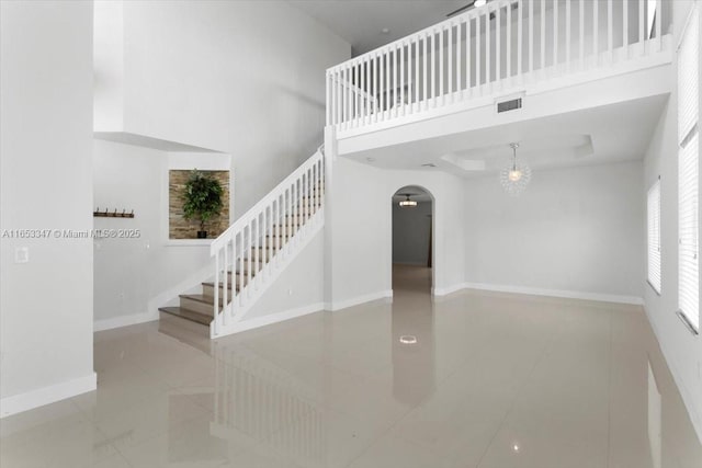 stairs with tile patterned flooring and a high ceiling