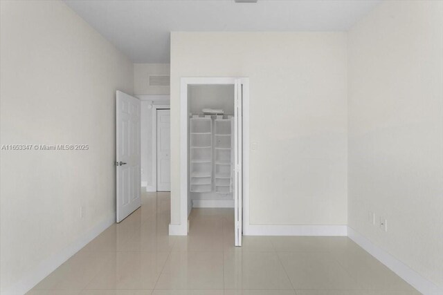 unfurnished bedroom with a spacious closet, a closet, and light tile patterned flooring